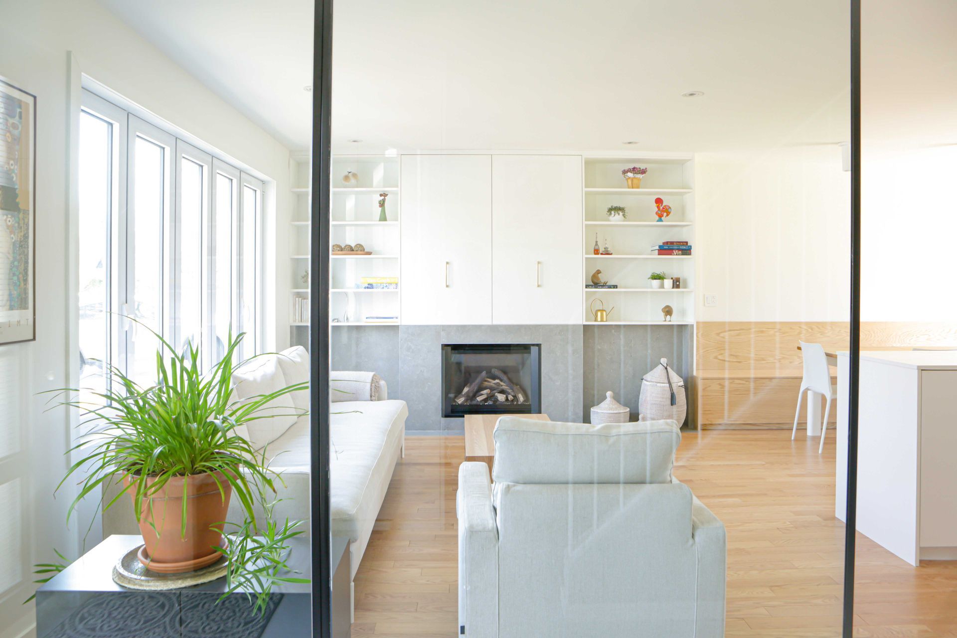 Un salon avec cheminée, canapé, chaise et plante en pot.