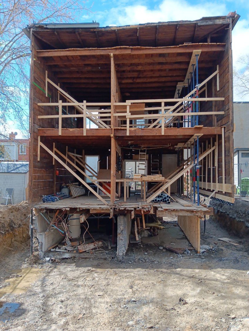 Une maison est en cours de construction avec des poutres en bois et des échafaudages.