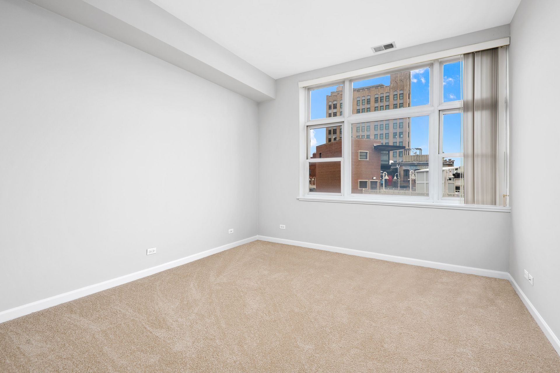 An empty room with a large window and a carpeted floor at 2010 West Pierce Avenue.