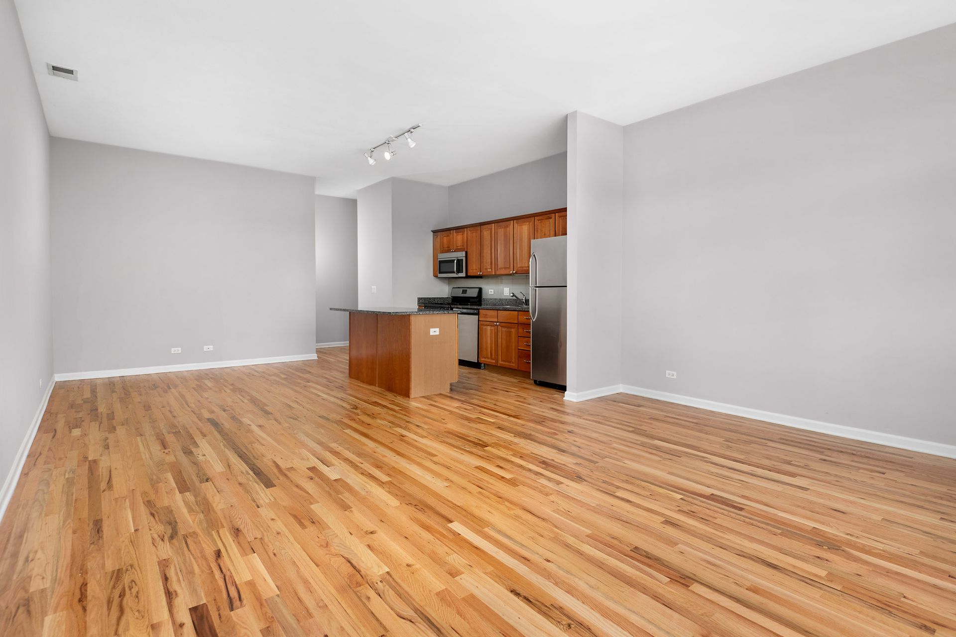 A living room with hardwood floors and a kitchen in the background at 2010 West Pierce Avenue.