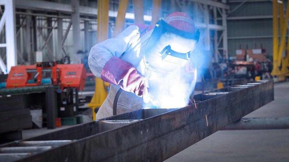 A Man Is Welding a Piece of Metal in A Factory — North Coast Steel in Macksville, NSW