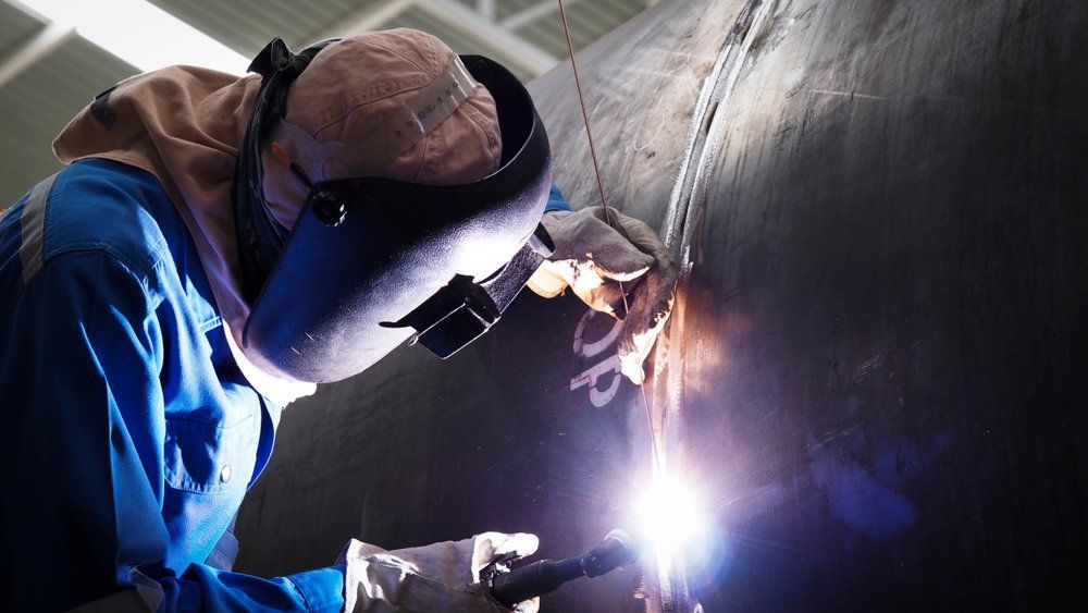 A Man Wearing a Welding Mask Is Welding a Pipe — North Coast Steel in Wauchope, NSW