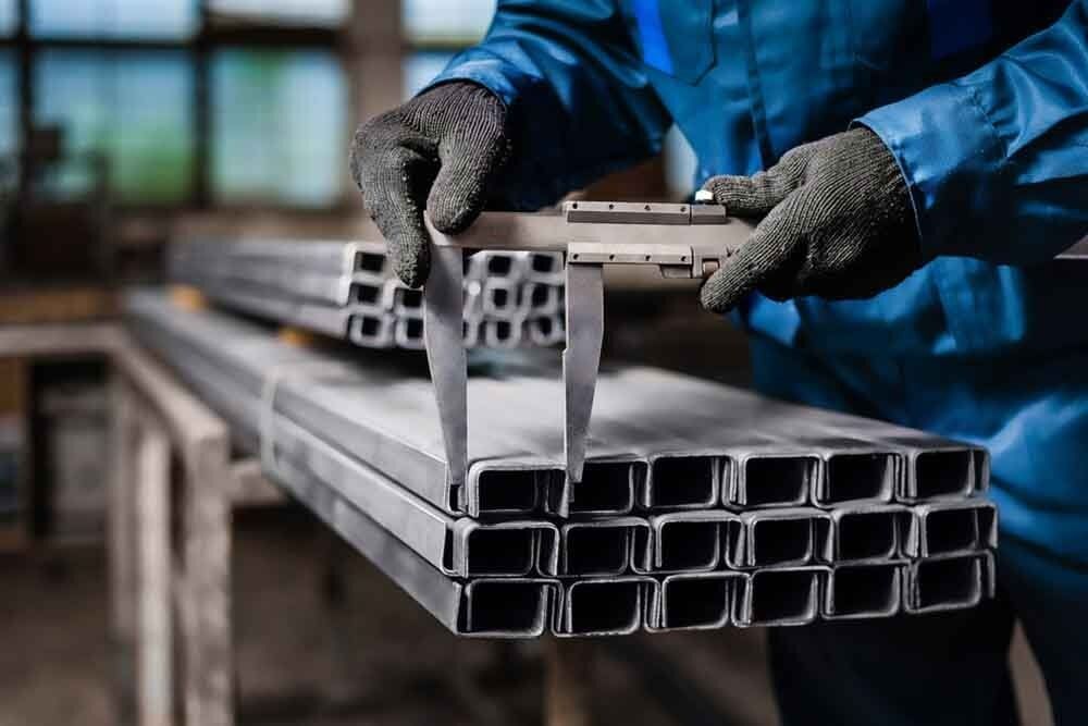 A Man Is Measuring a Stack of Metal Pipes with A Caliper — North Coast Steel in South Kempsey, NSW