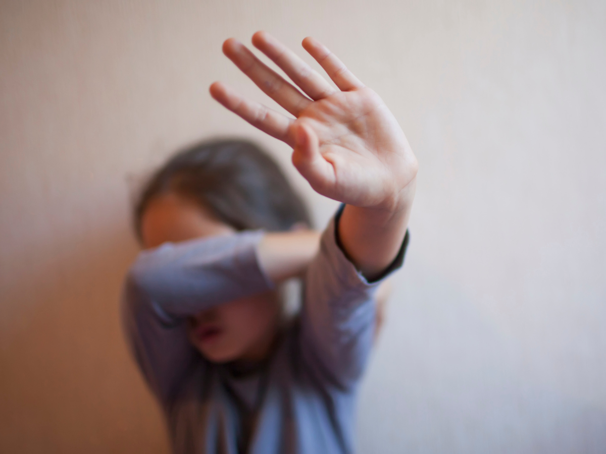 A young girl is covering her face with her hand.