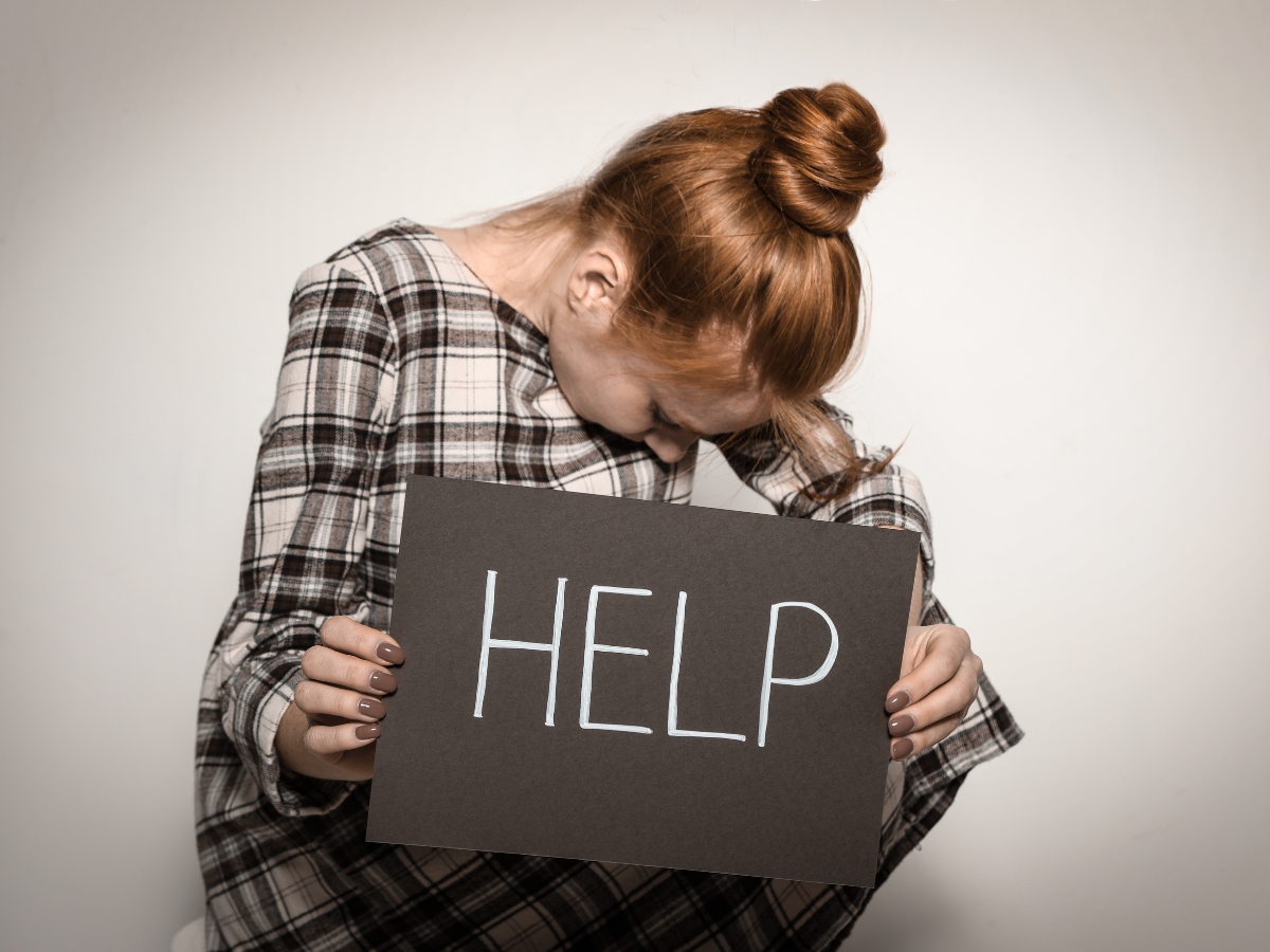 A woman is holding a sign that says help.