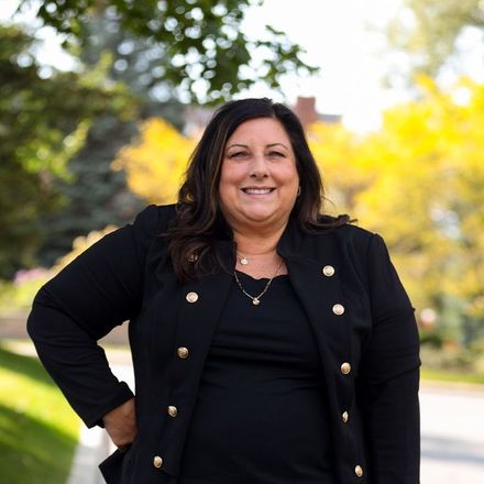 A woman in a black jacket is smiling for the camera