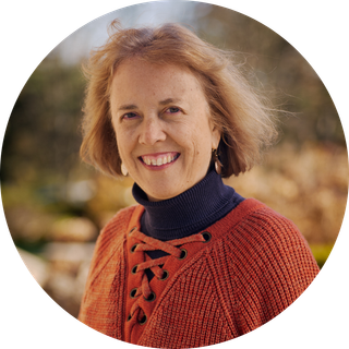 A woman in an orange sweater is smiling in a circle