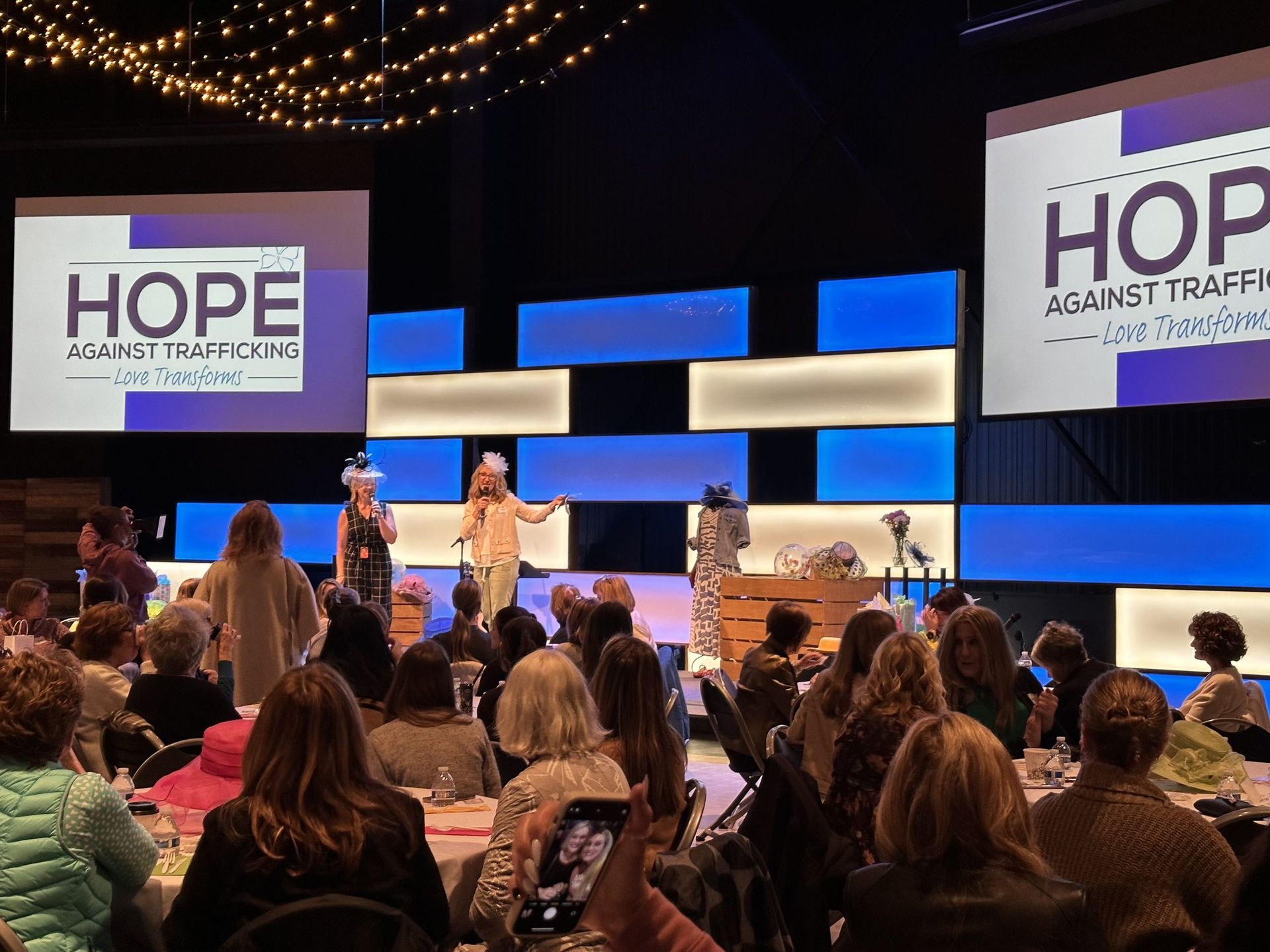 A group of people are sitting in front of a stage at a conference.