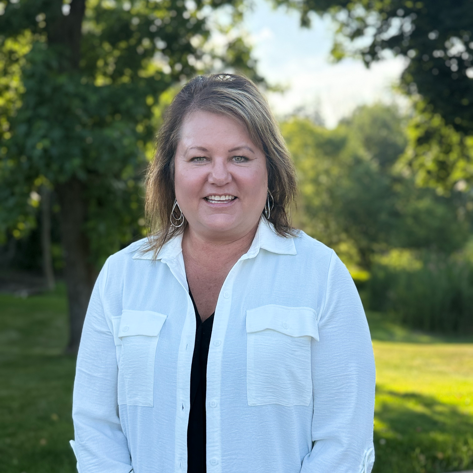 A woman in a white shirt is smiling for the camera.