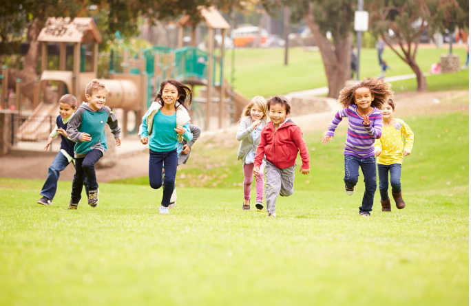 A group of children are running in a park.