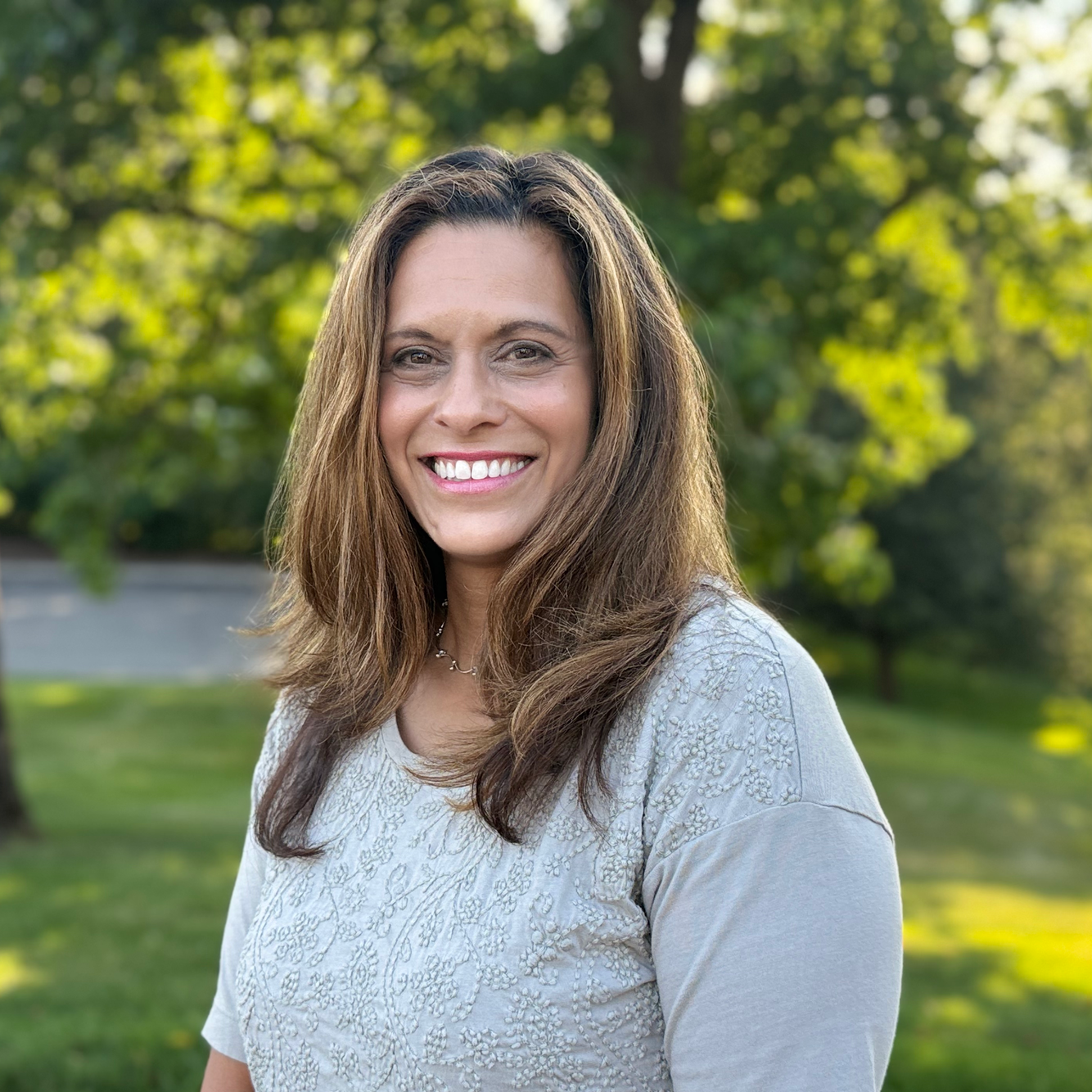 A woman is smiling for the camera in a park.