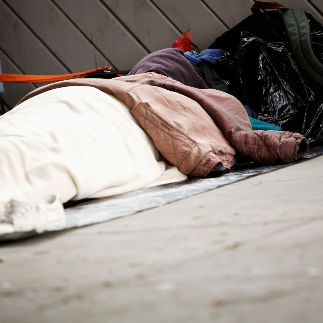 Hope Against Trafficking / A homeless person is lying on the ground in a pile of blankets