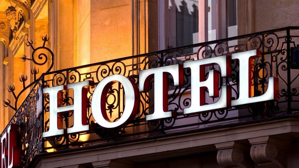 Hope Against Trafficking | A hotel sign in illuminated letters on the railing of a building's balcony with ornate ironwork.