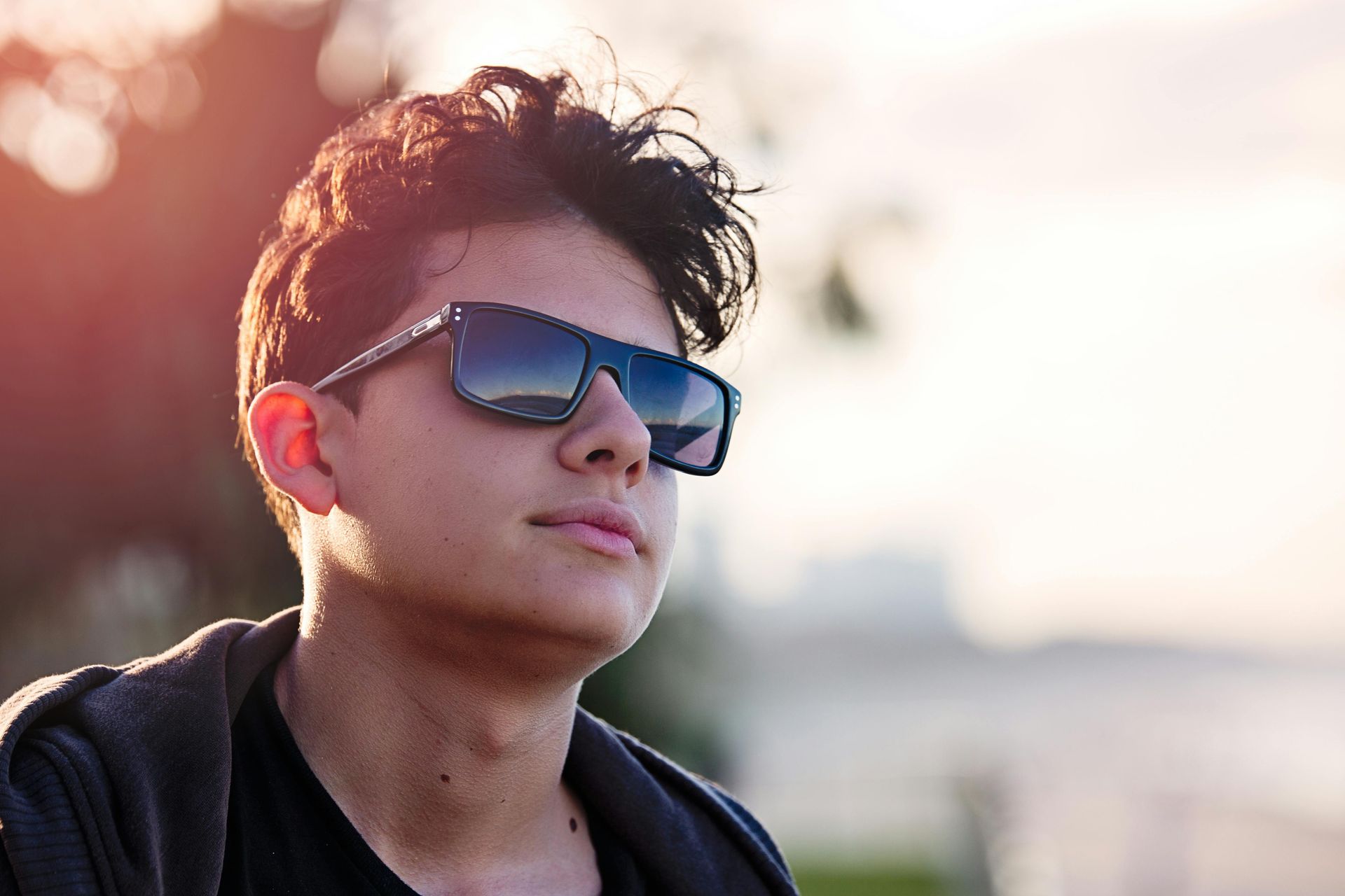 A young man wearing sunglasses is looking away from the camera.