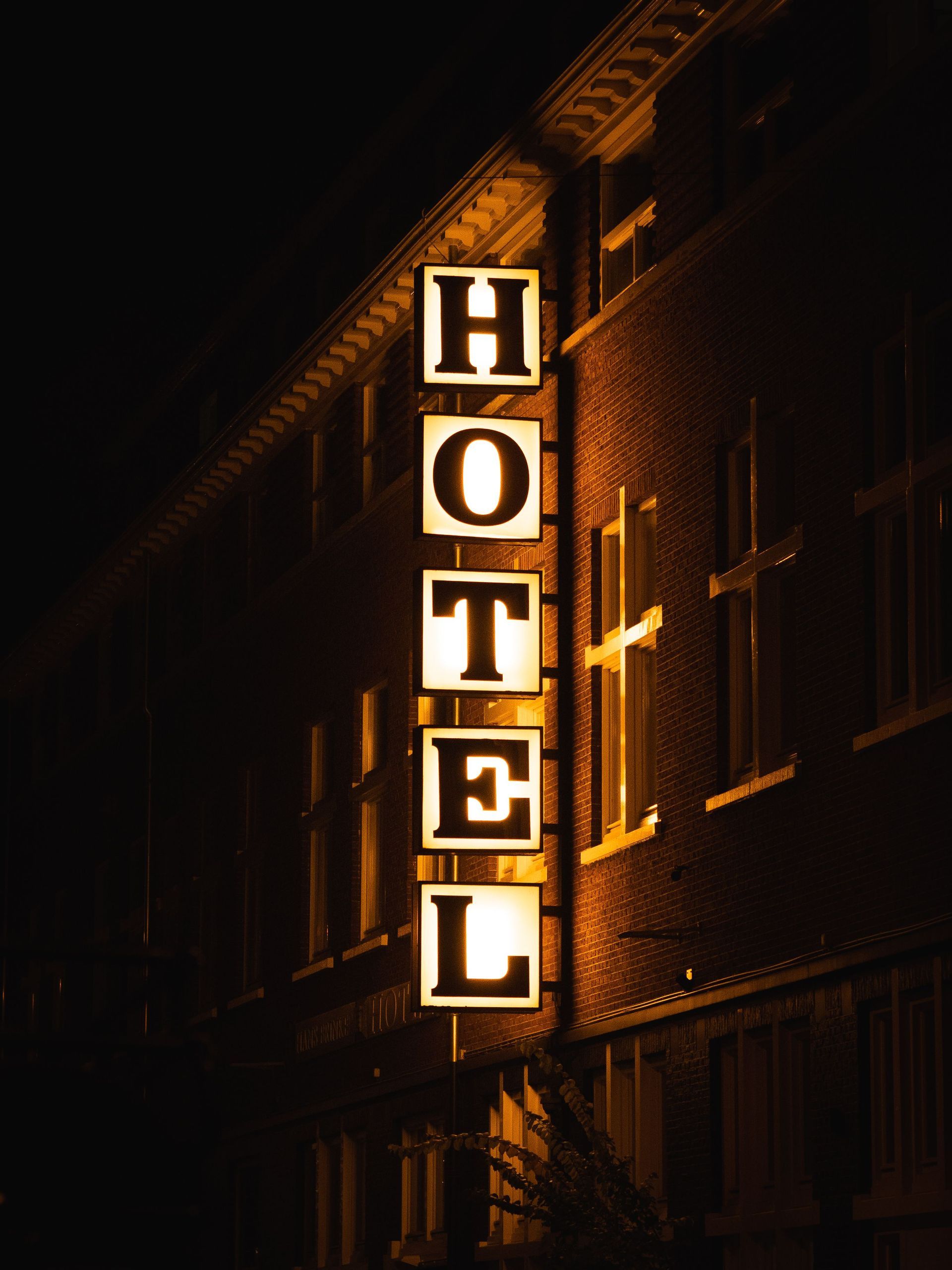 Vertical neon hotel sign glowing at night on a dark building facade