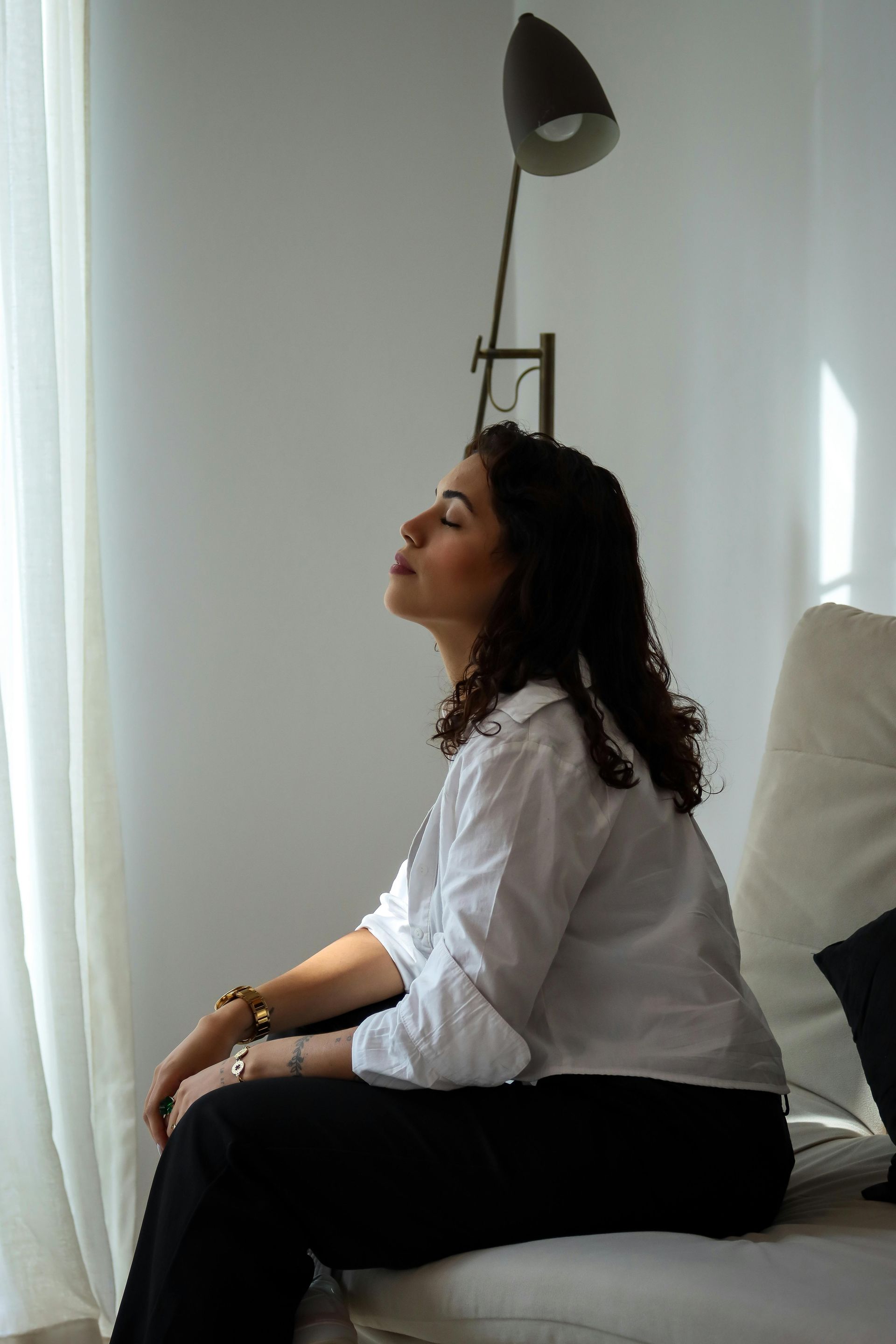 A woman is sitting on a couch with her eyes closed.