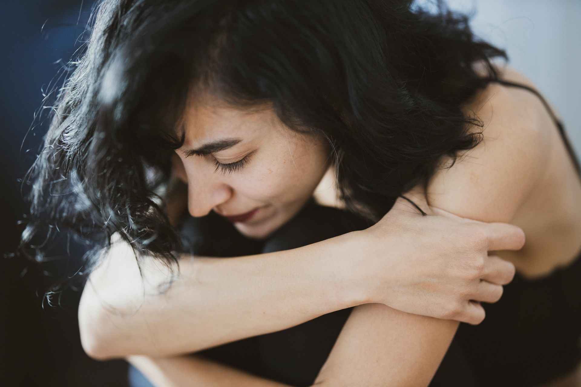 A woman in a black shirt is hugging herself and scared.