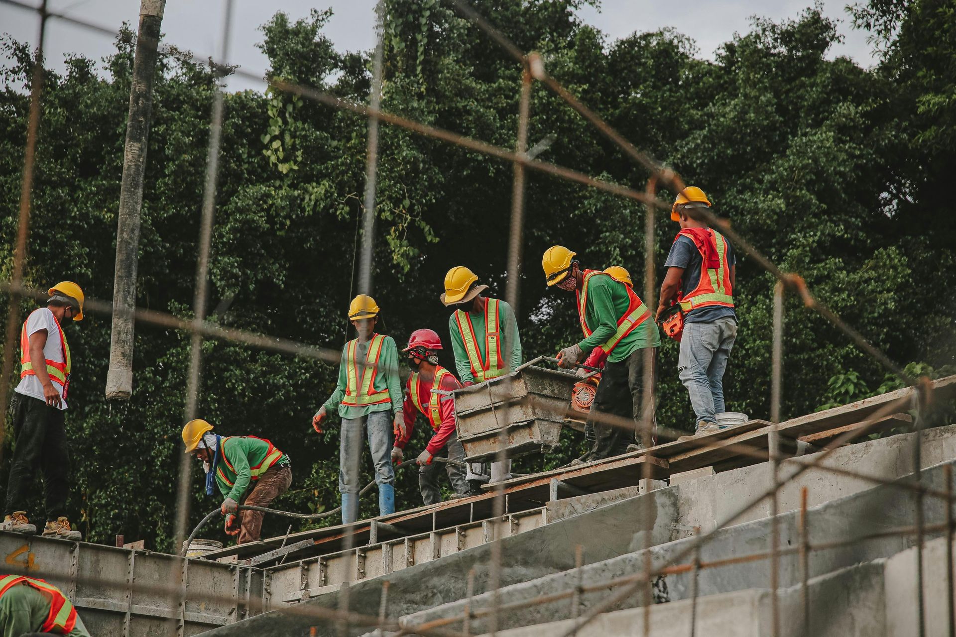 Construction workers in yellow helmets on a sloped scaffold, lifting materials at a building site.