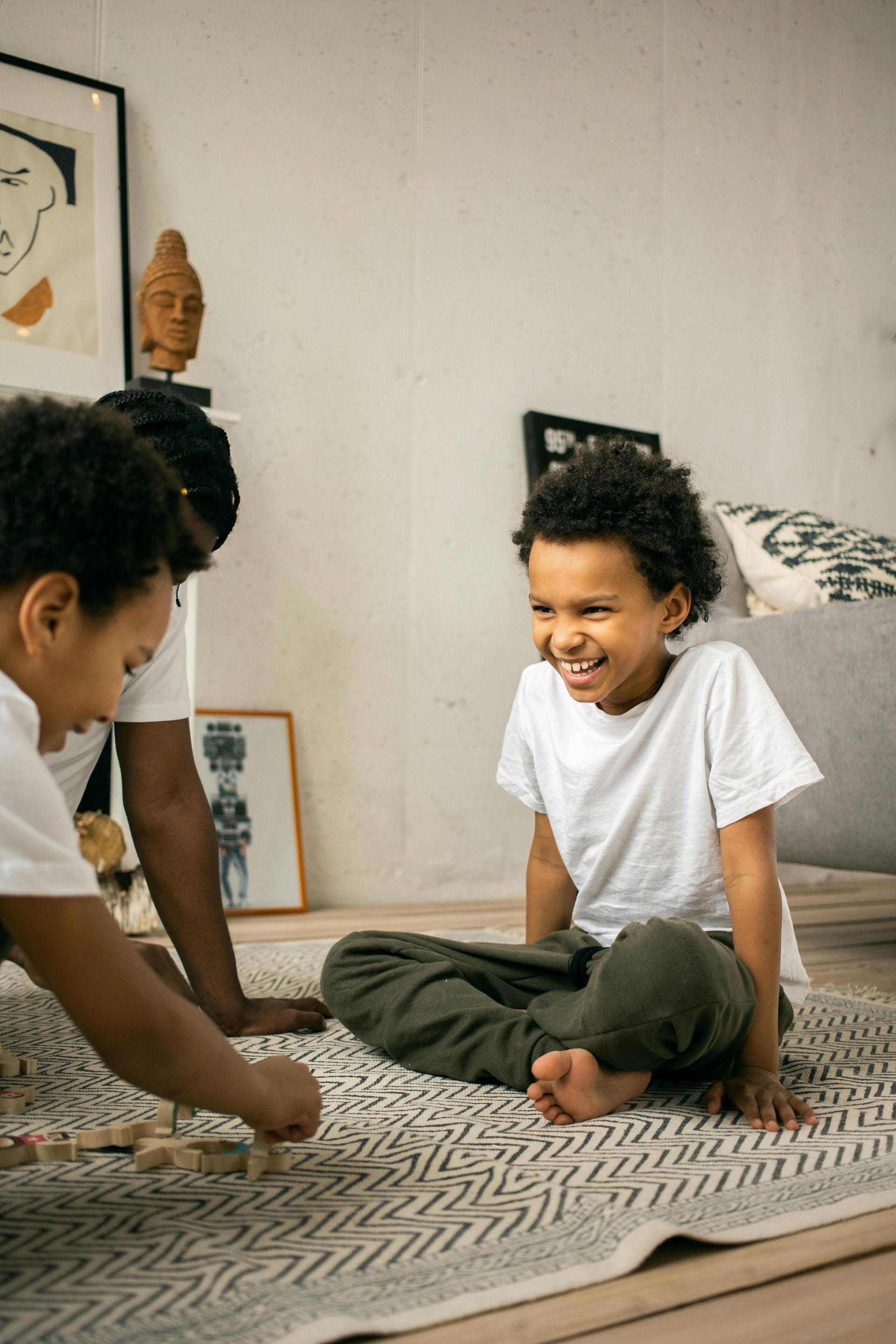 A man and two children are sitting on a rug playing a game.