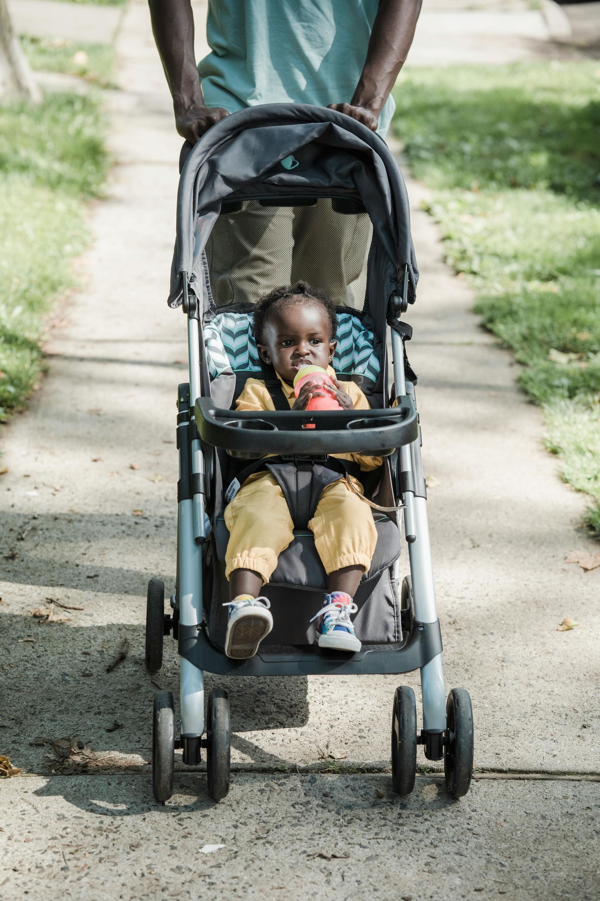 A baby is sitting in a stroller on a sidewalk.