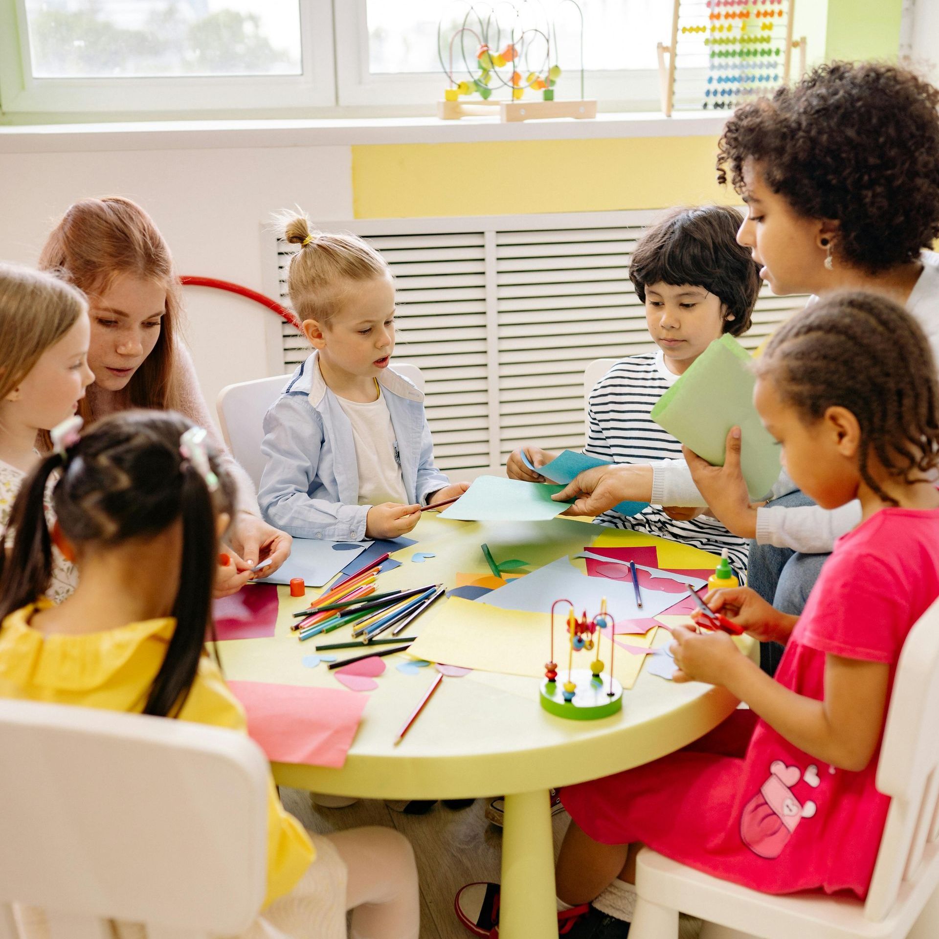 A group of children are sitting around a table playing with toys.