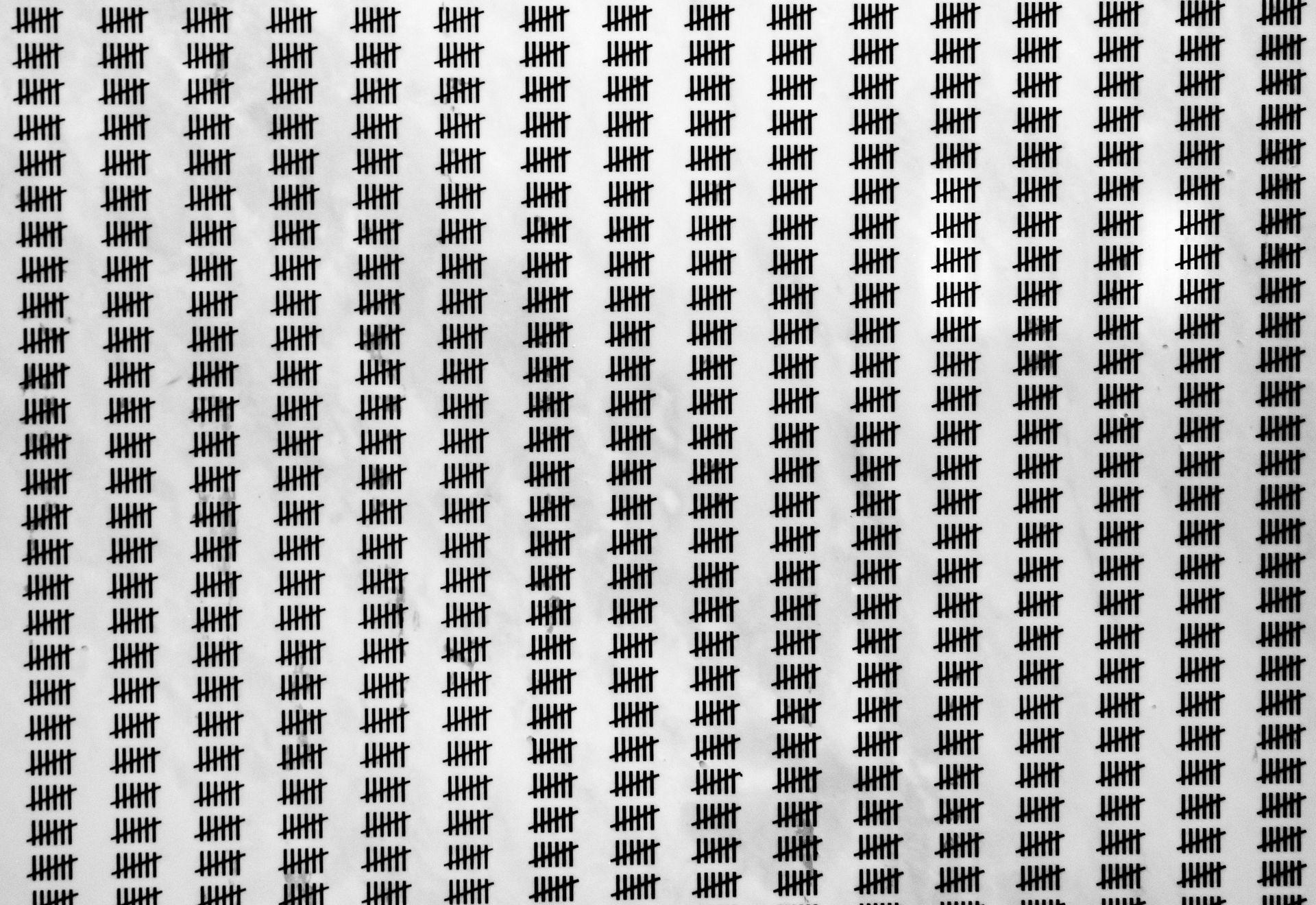 Repetitive pattern of tally marks written in black, closely spaced, against a gray background.