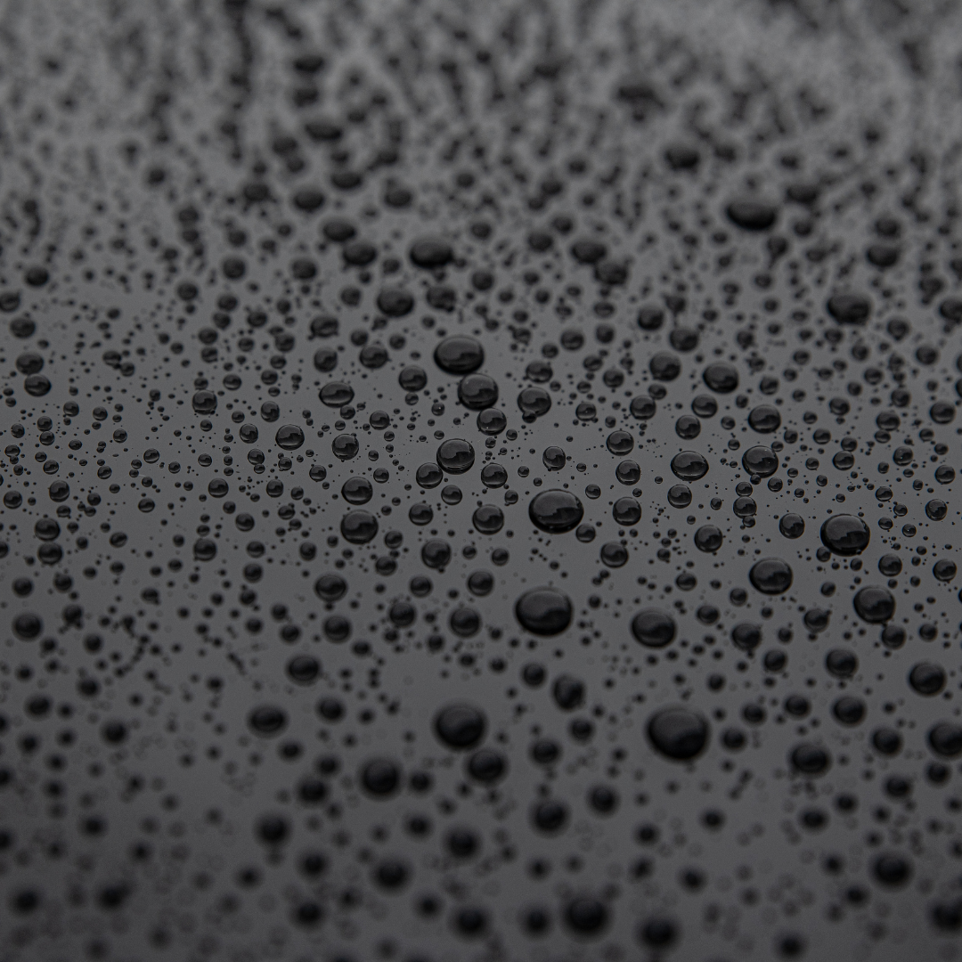 a close up of water drops on a black surface .
