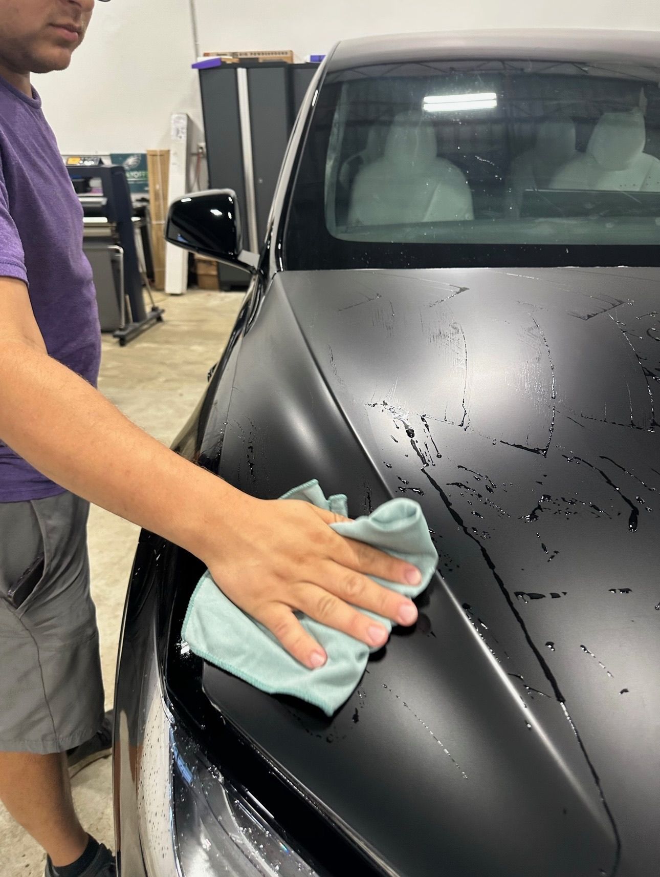 a man is cleaning a black car with a cloth .
