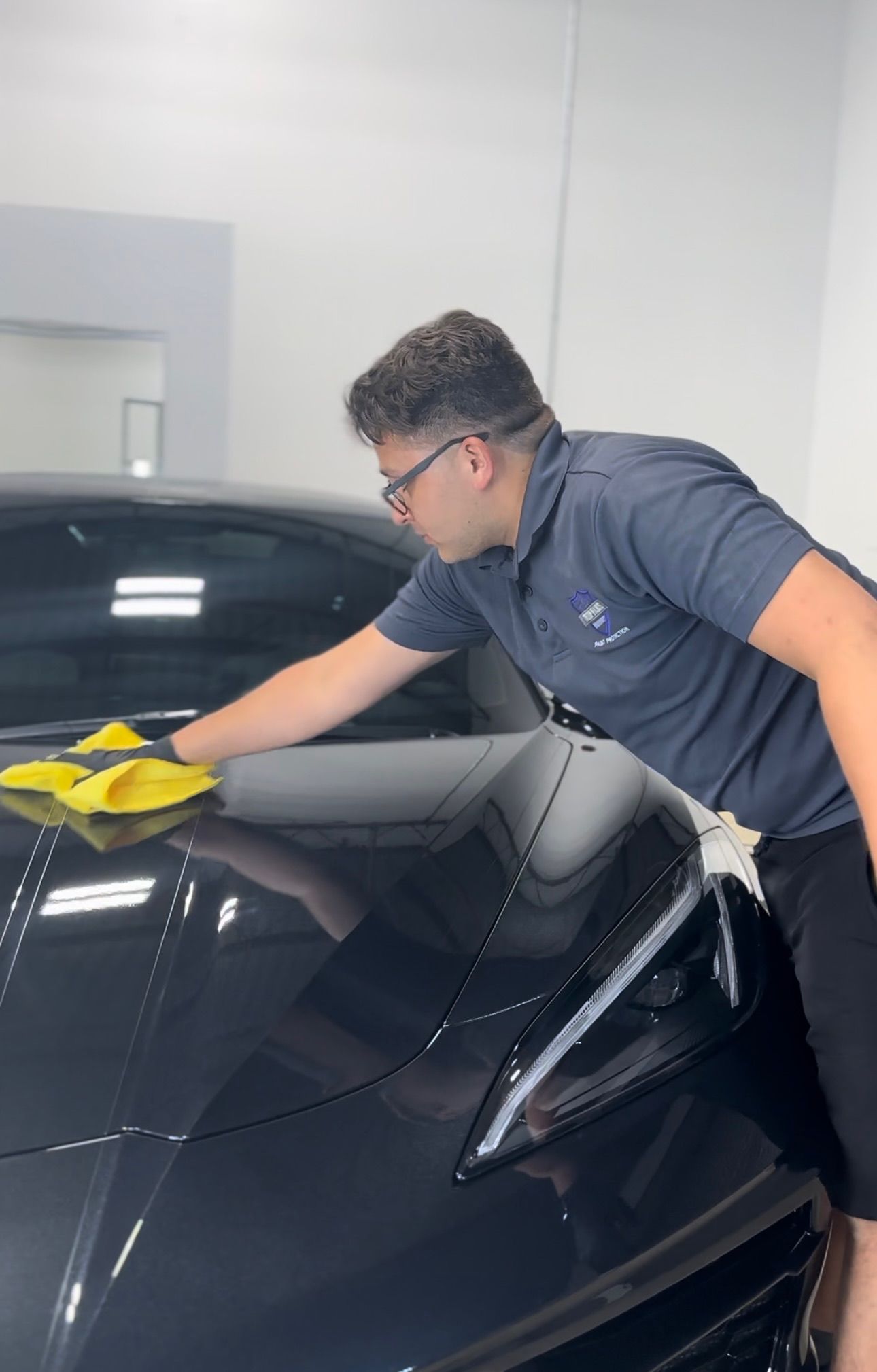 a man is cleaning the hood of a black car with a cloth .