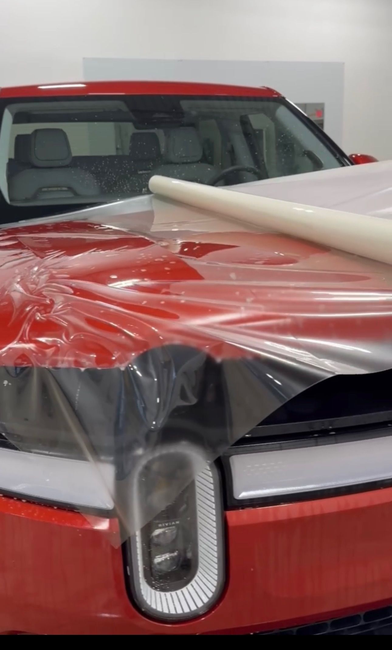 a red car is covered in plastic wrap in a garage .