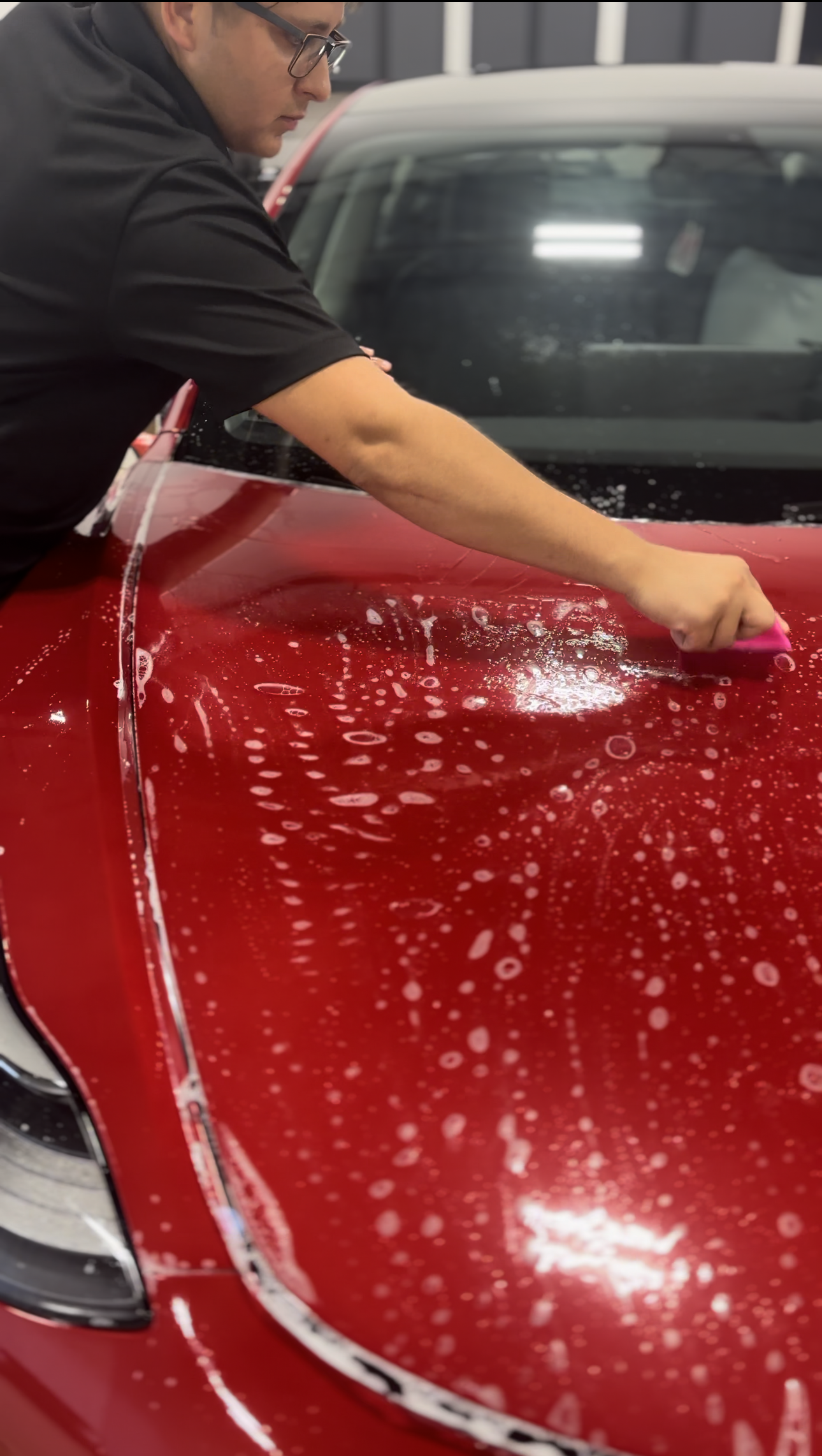 a man is cleaning the hood of a red car
