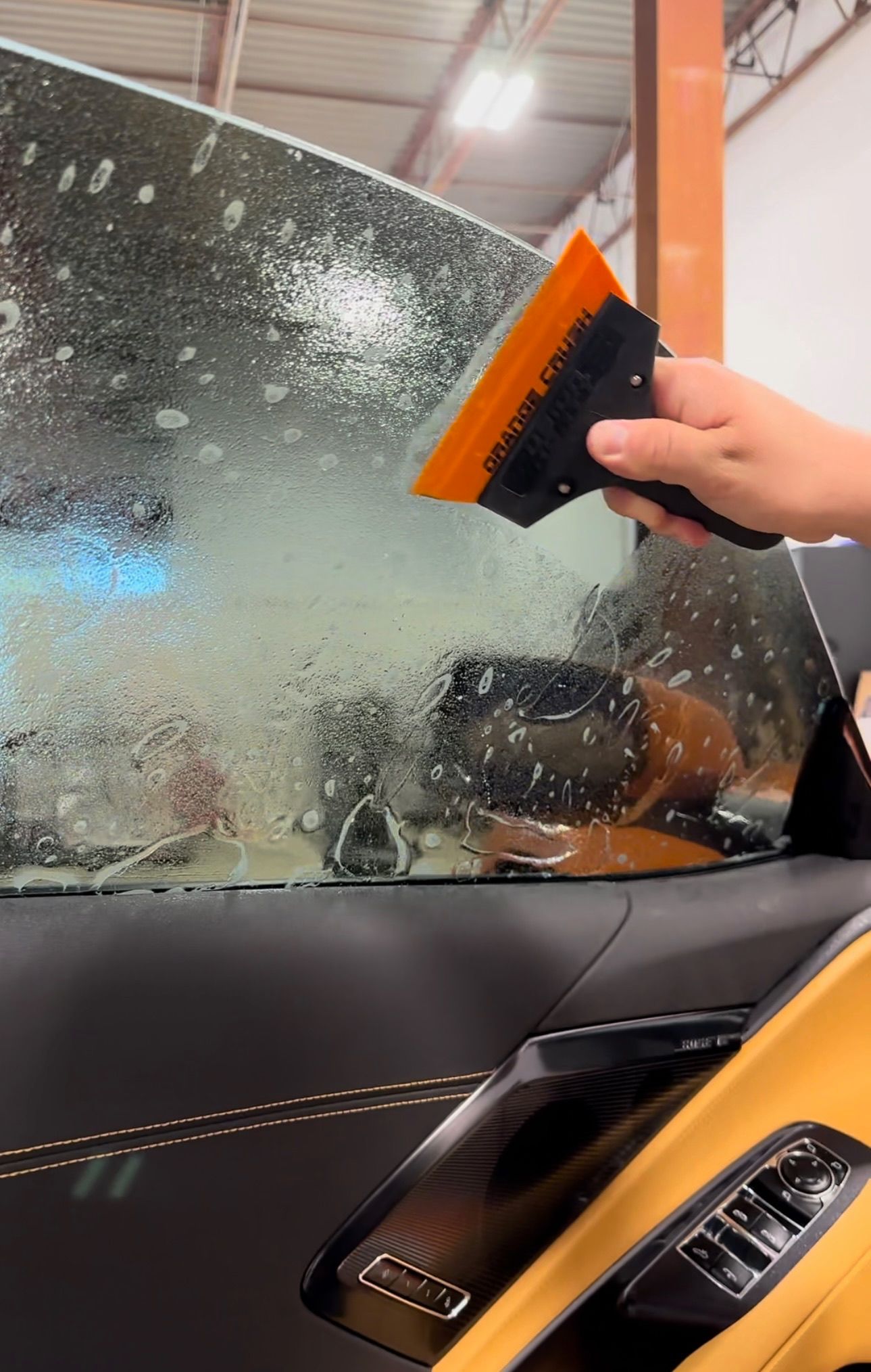 a person is holding a squeegee over a car window .
