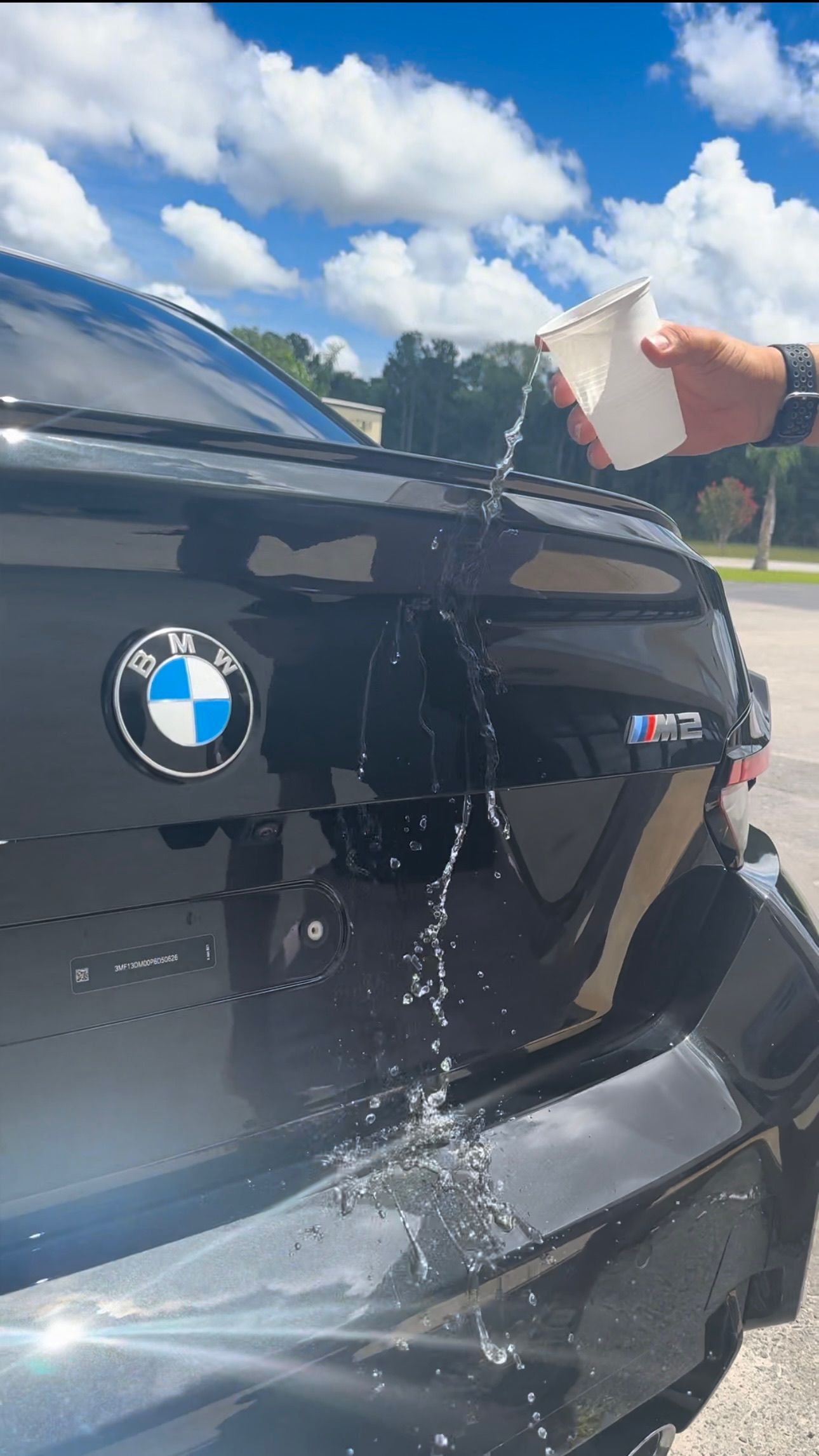 a person is pouring water into the trunk of a bmw .