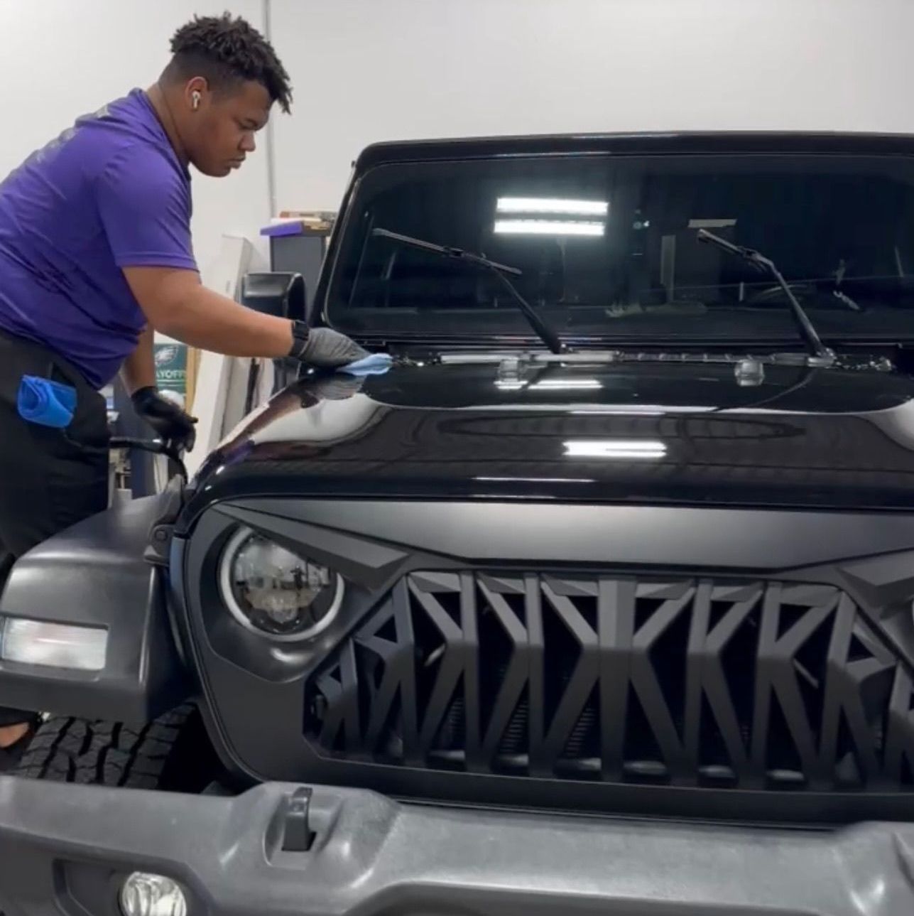 a man in a purple shirt is working on a jeep