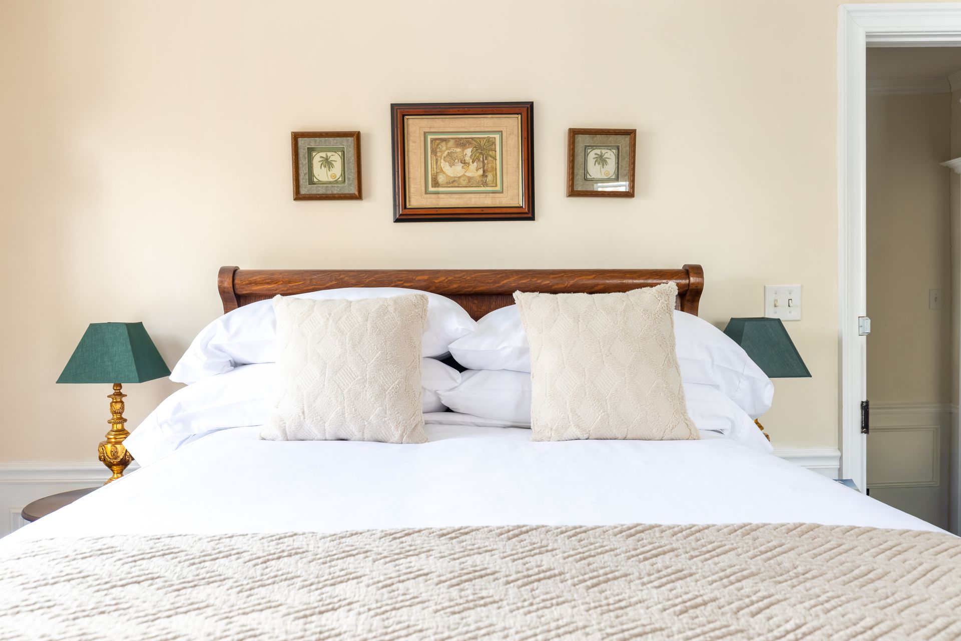 Bedroom with a bed, two pillows, artwork above the headboard, and bedside lamps.