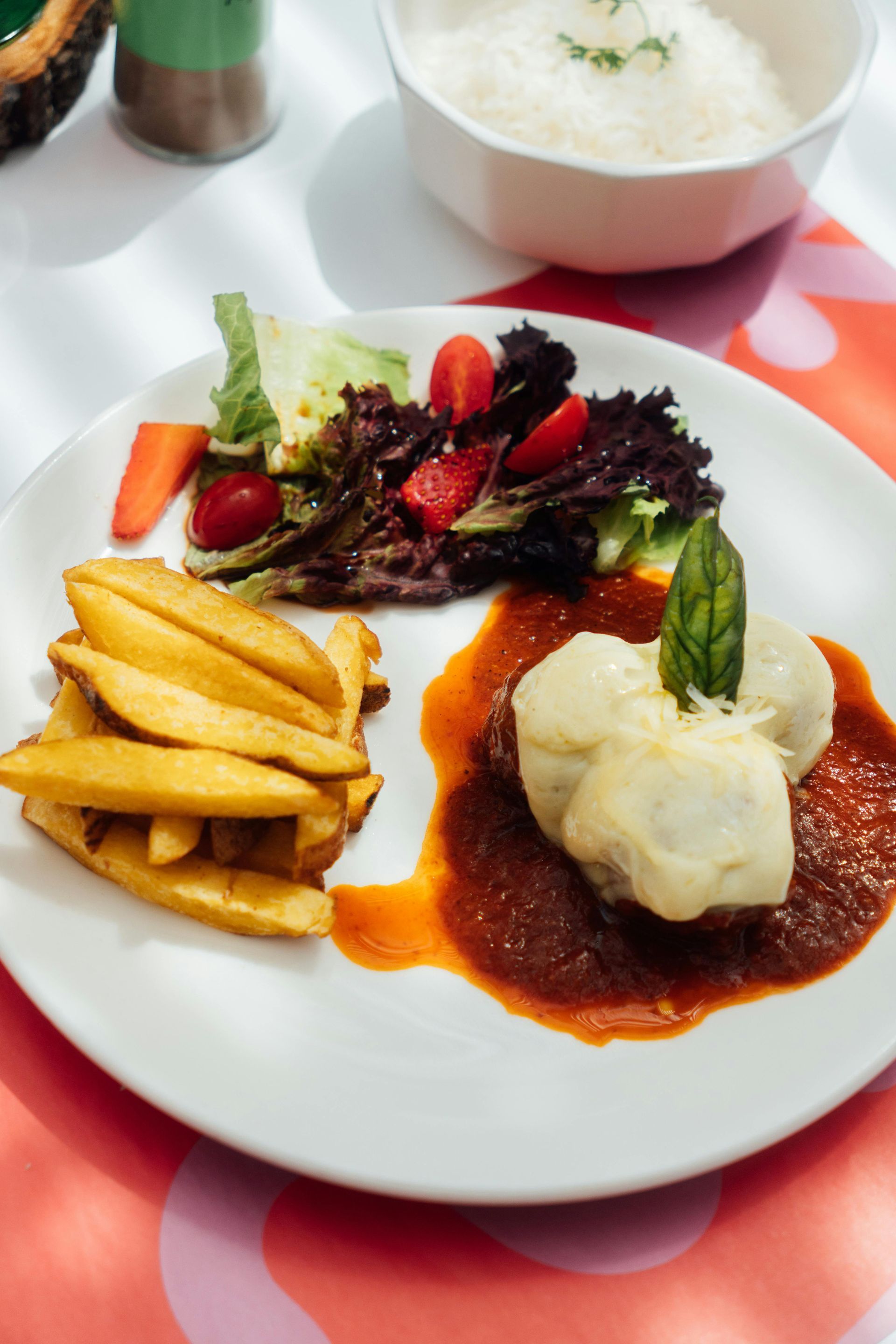 Plate of food: meat, mashed potatoes, fries, salad, and rice.