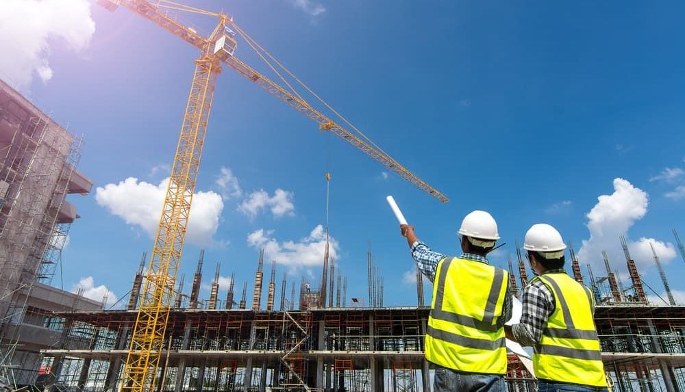 Two Construction Workers Are Looking at a Crane — Coastal Surveying Group Pty Ltd in Baringa, QLD
