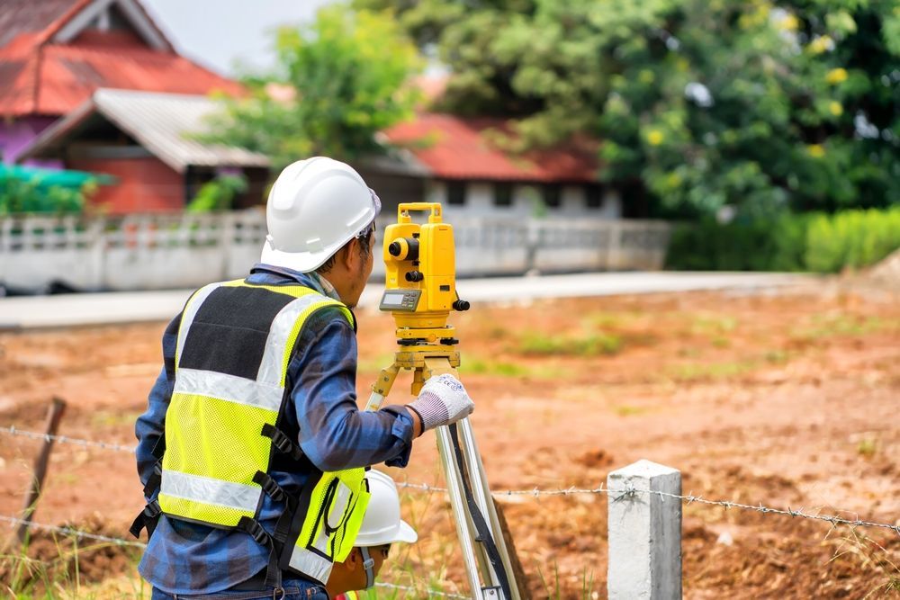 A Construction Worker is Using a Theodolite on a Construction Site — Coastal Surveying Group Pty Ltd in Baringa, QLD