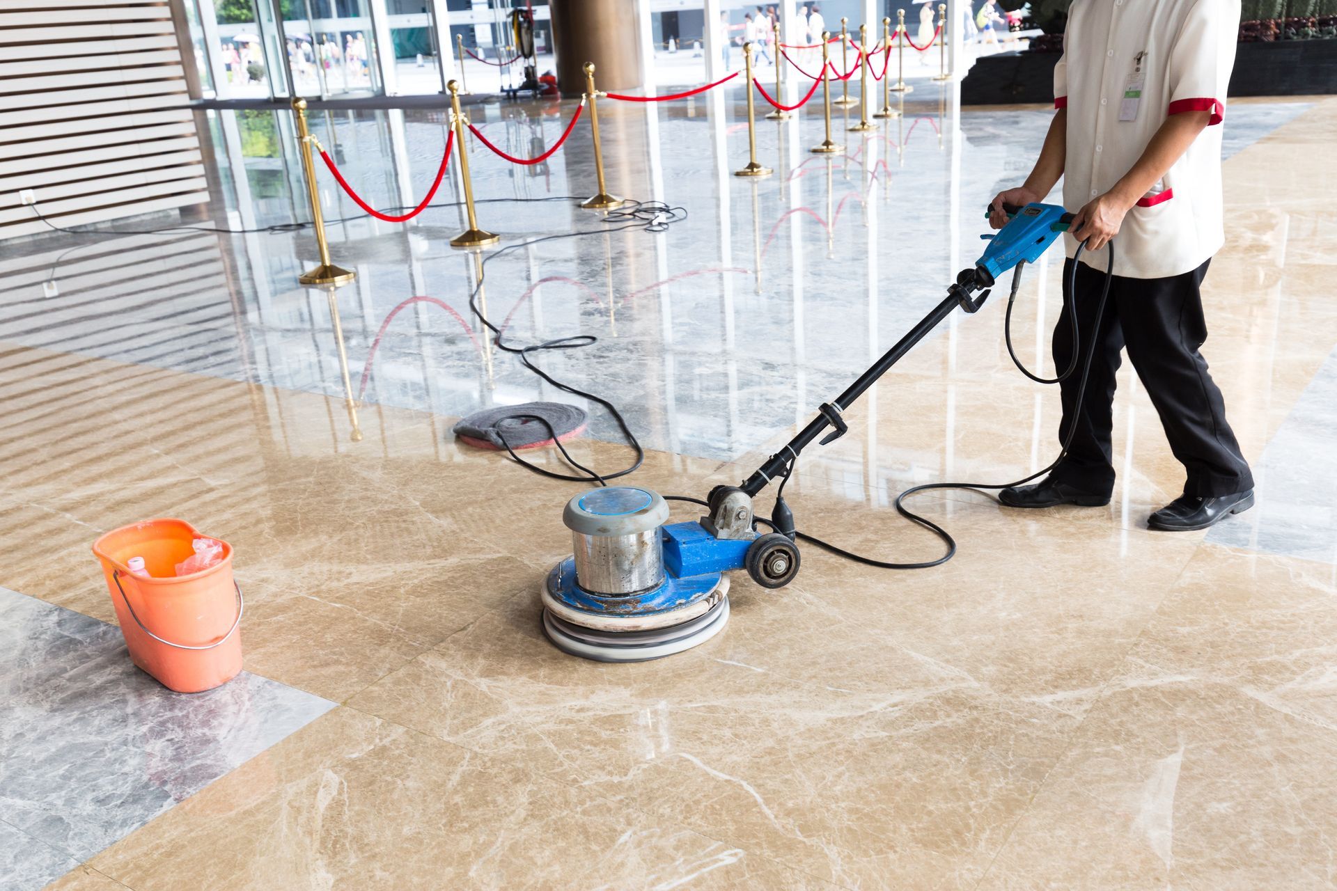 A man is cleaning a marble floor with a machine.