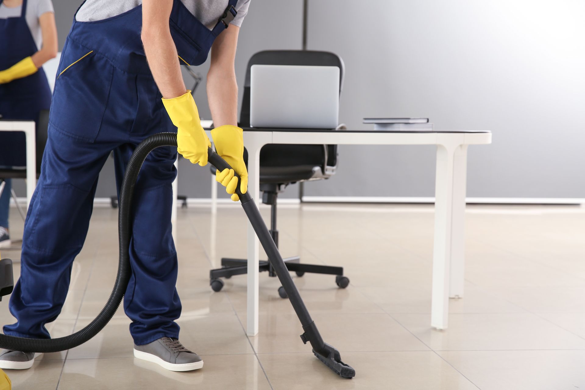 A man is using a vacuum cleaner to clean an office floor.
