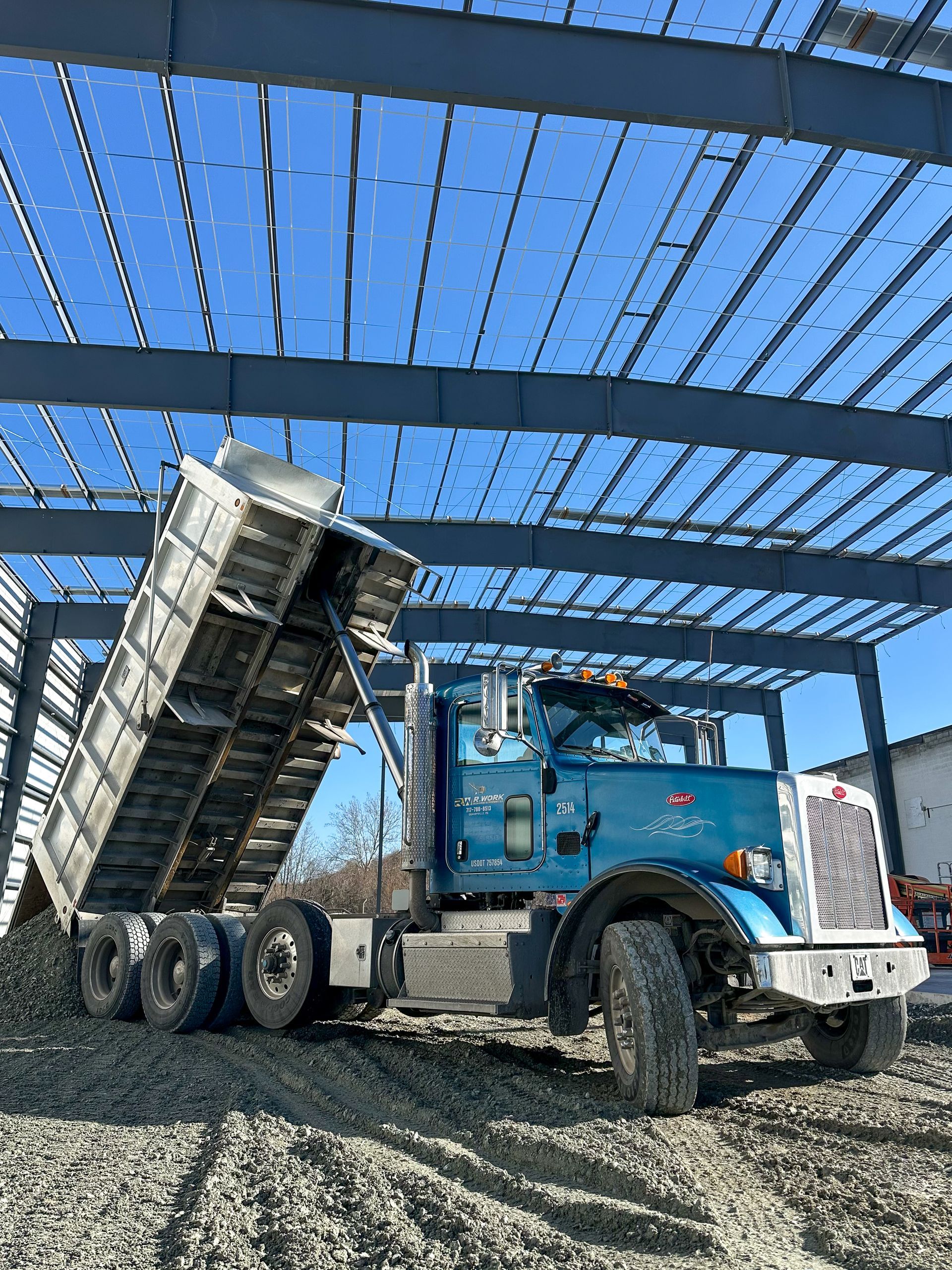 A dump truck from R. Work Excavating & Trucking is parked in front of a building under construction.