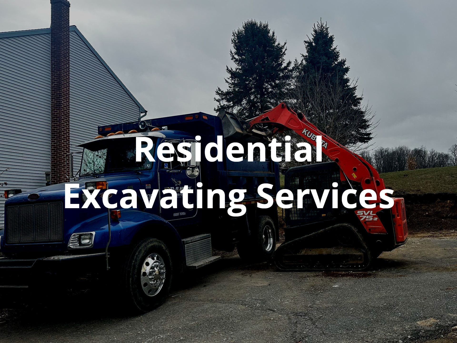 A blue truck and a red excavator from R. Work Excavating & Trucking are parked in front of a house.