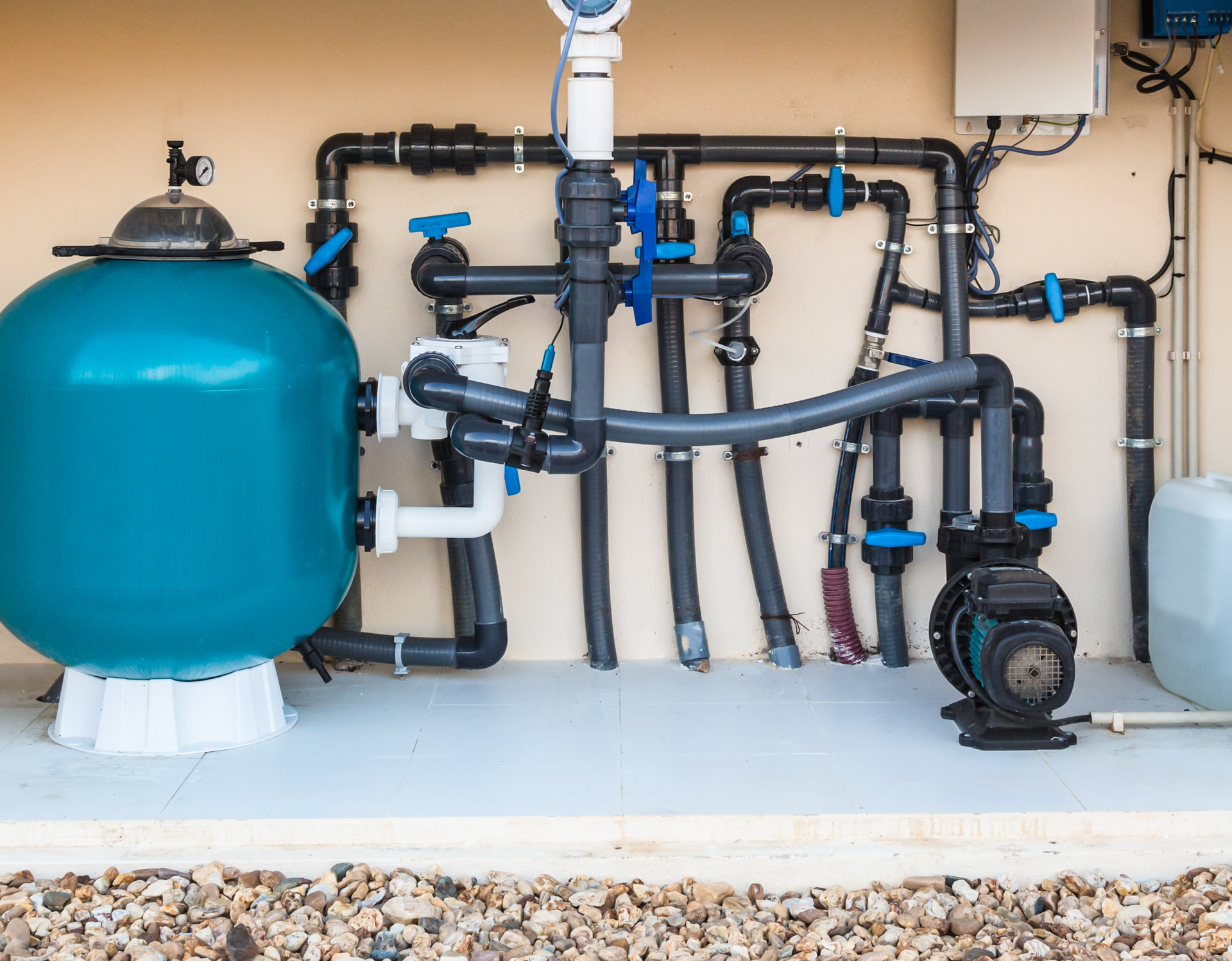 A swimming pool filter is sitting next to a pump and pipes. A swimming pool filter is sitting next to a pump and pipes.