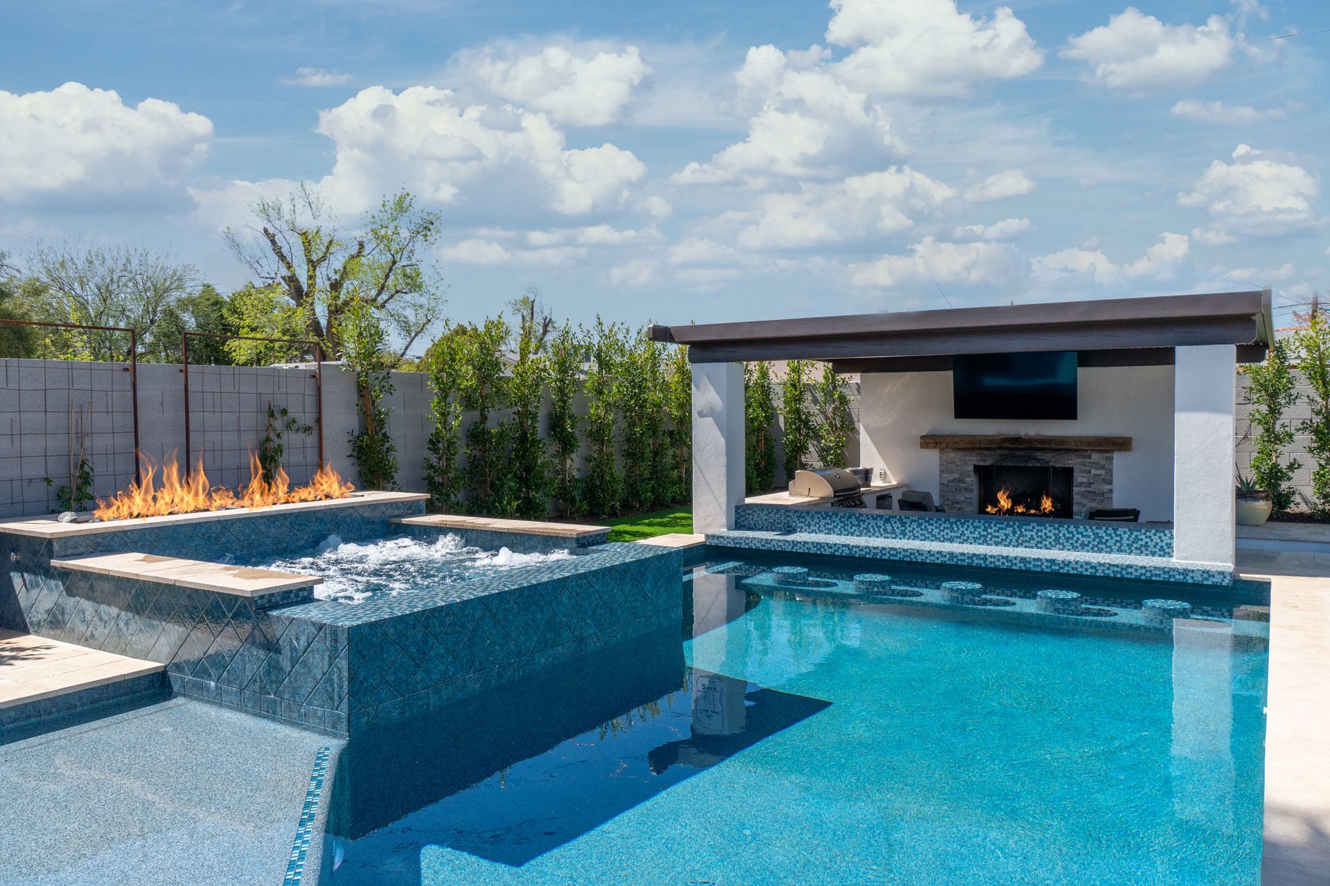 A large swimming pool with a fireplace in the backyard.