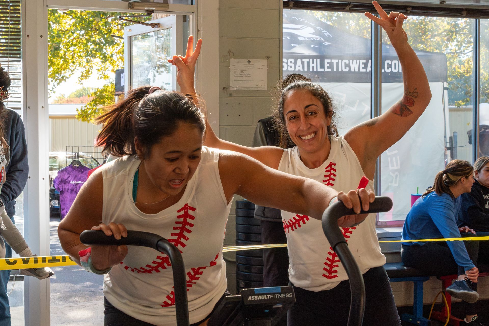 Two women are riding exercise bikes in a gym.