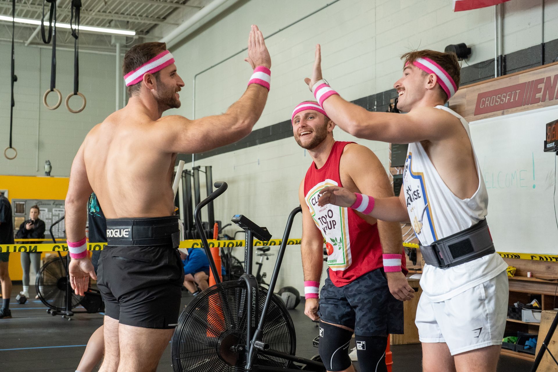 Three men are giving each other a high five in a gym.
