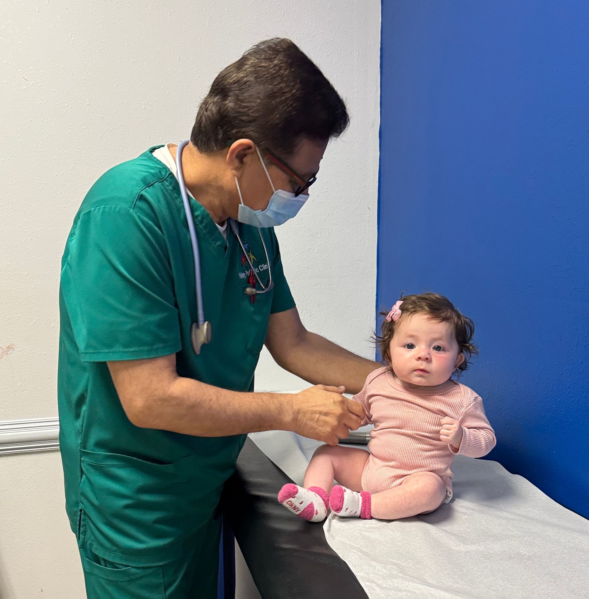 A baby is being examined by a pediatrician  who is wearing a mask