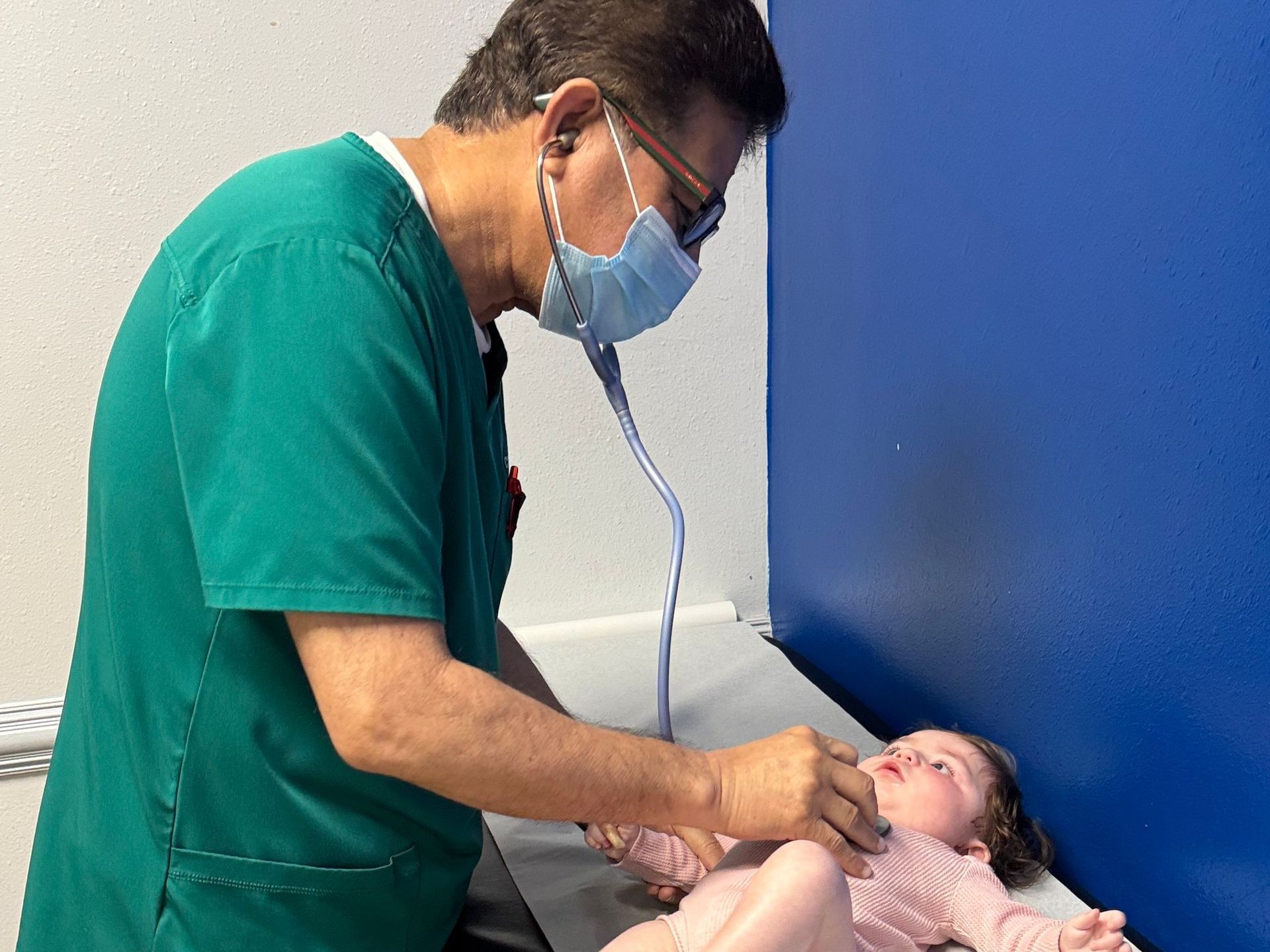 A pediatrician is examining a baby with a stethoscope.