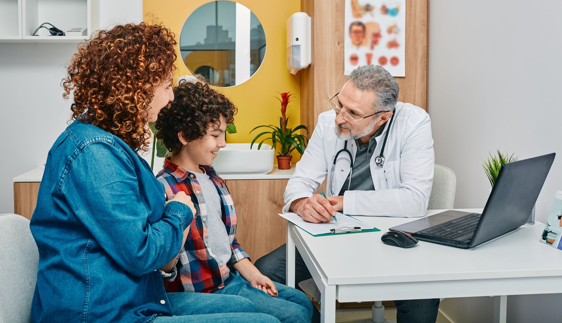 A pediatrician is talking to a child and his mother in a doctor 's office.