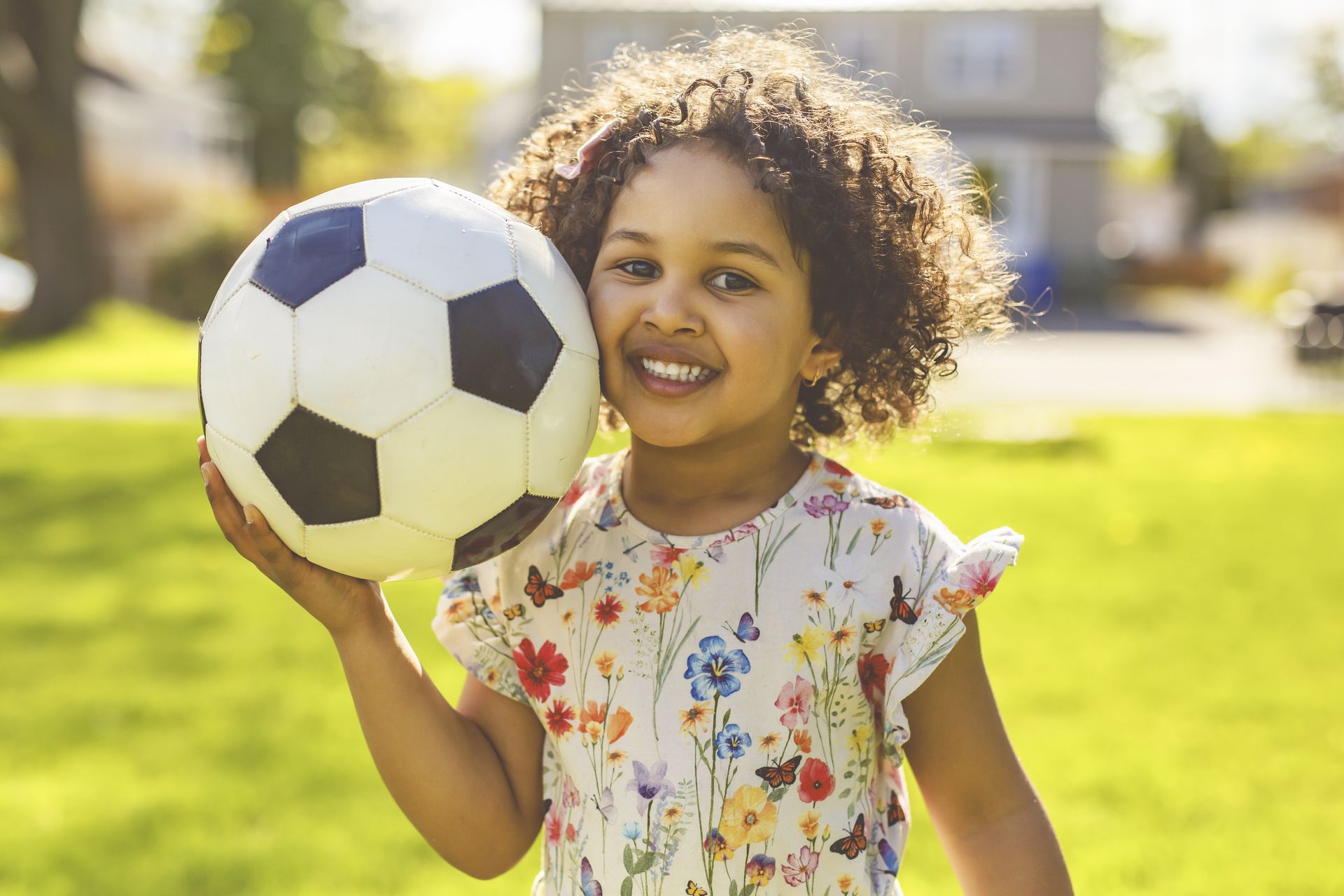 A little girl is holding a soccer ball in her hands.